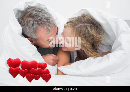 Immagine composita di amorevole coppia di mezza età sotto il piumino Foto Stock