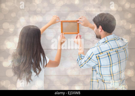 Immagine composita di felice coppia giovane mettendo su cornice immagine Foto Stock