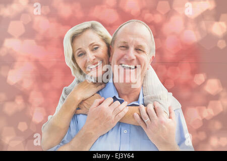 Immagine composita di felice coppia matura abbracciando sorridente in telecamera Foto Stock