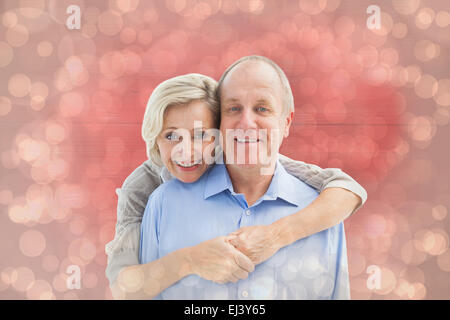 Immagine composita di felice coppia matura abbracciando sorridente in telecamera Foto Stock