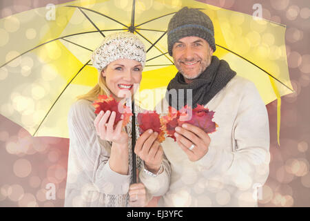 Immagine composita del giovane in inverno la moda che mostra le foglie di autunno sotto ombrellone Foto Stock