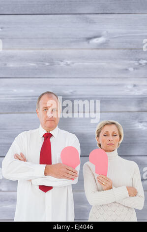 Immagine composita della coppia di anziani in piedi tenendo rotto cuore rosa Foto Stock