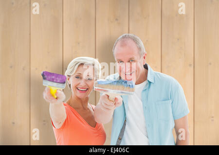 Immagine composita di felice coppia di anziani azienda pennelli Foto Stock