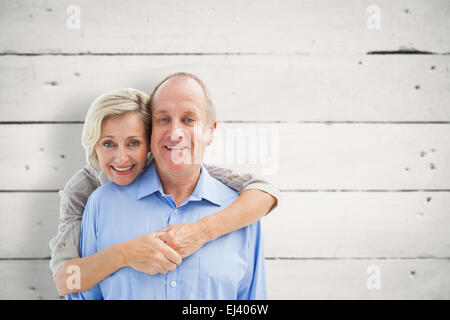 Immagine composita di felice coppia matura abbracciando sorridente in telecamera Foto Stock