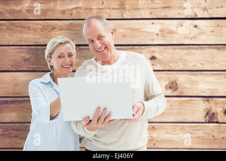 Immagine composita di felice coppia matura utilizzando laptop Foto Stock