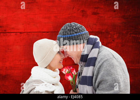 Immagine composita di felice coppia matura in abbigliamento invernale con rose Foto Stock