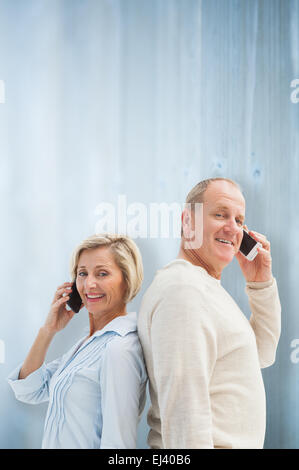 Immagine composita di felice coppia matura parlando sui loro telefoni Foto Stock