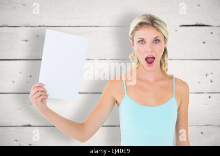 Immagine composita di scioccato bionda tenendo un foglio di carta Foto Stock