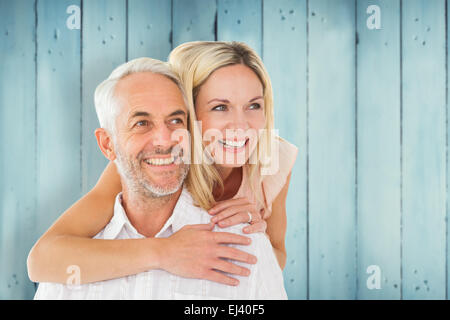 Immagine composita di uomo felice di dare il suo partner un piggy back Foto Stock