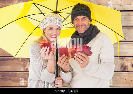 Immagine composita del giovane in inverno la moda che mostra le foglie di autunno sotto ombrellone Foto Stock