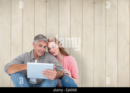 Immagine composita di casual giovane seduta utilizzando tablet Foto Stock