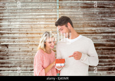 Immagine composita della coppia attraente tenendo in miniatura Modello di casa Foto Stock