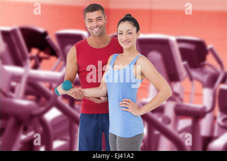 Immagine composita di montare la donna e il trainer sorridente in telecamera Foto Stock