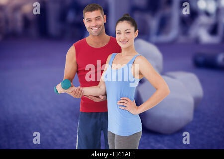 Immagine composita di montare la donna e il trainer sorridente in telecamera Foto Stock