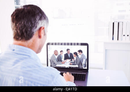 Immagine composita dell uomo con i capelli grigi usando il suo computer portatile Foto Stock