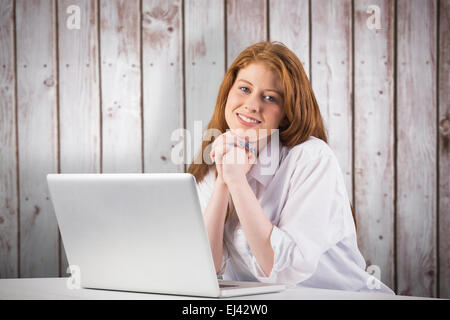 Immagine composita di pretty redhead lavorando sul computer portatile Foto Stock