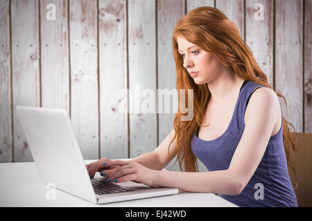 Immagine composita di pretty redhead lavorando sul computer portatile Foto Stock