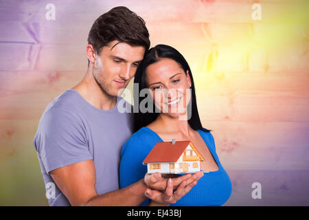 Immagine composita della coppia giovane tenendo un modello di casa Foto Stock