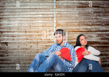 Immagine composita della coppia giovane seduto sul pavimento con cuore spezzato Foto Stock