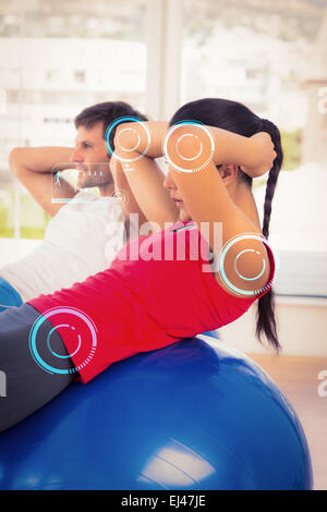 Immagine composita di montare la coppia giovane esercitando sulle sfere di fitness in palestra Foto Stock