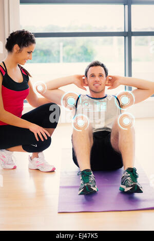 Immagine composita del trainer femmina guardare l uomo non sgranocchia addominali sul tappetino di esercizio Foto Stock