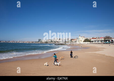 Le donne a piedi i loro cani su una spiaggia a Estoril, Portogallo. Foto Stock