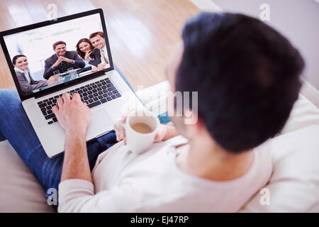 Immagine composita di elevato angolo di visione del giovane uomo usando il suo computer portatile Foto Stock