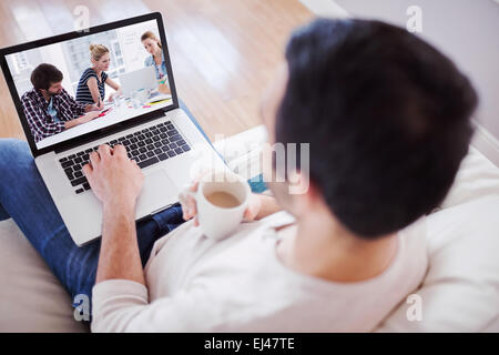 Immagine composita di elevato angolo di visione del giovane uomo usando il suo computer portatile Foto Stock