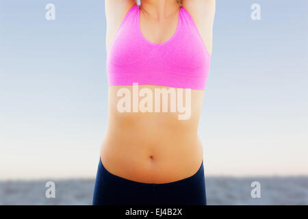 Immagine composita di sorridere tonica donna stretching mani sulla spiaggia Foto Stock