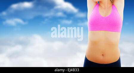 Immagine composita di sorridere tonica donna stretching mani sulla spiaggia Foto Stock