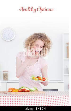 Opzioni di sani contro la bella donna bionda mangiare alcune verdure in cucina Foto Stock