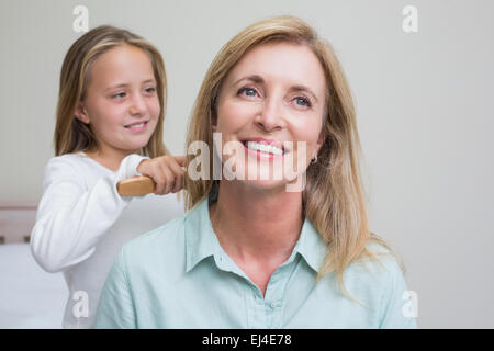 Ragazza carina la spazzolatura le mamme capelli Foto Stock