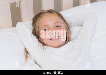 Felice bambina giacente nel suo letto Foto Stock