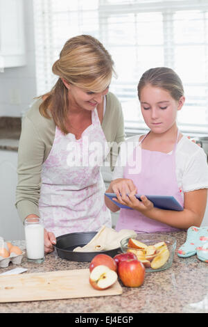 Felice madre e figlia torta di preparare insieme con la compressa Foto Stock