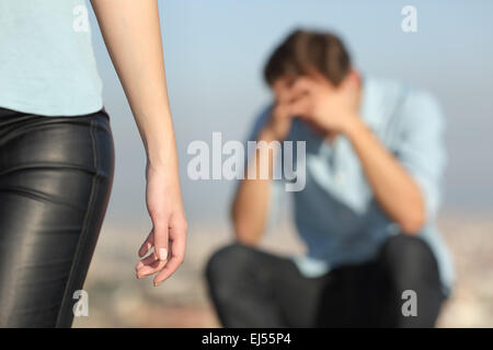 Scioglimento di un giovane con un triste uomo in background e la ragazza lasciando lui in primo piano Foto Stock