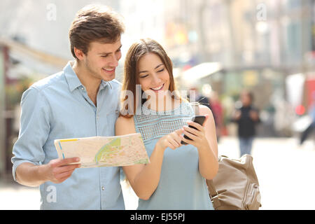 Coppia di turisti consultando la guida di una città e gps dello smartphone in strada alla ricerca posizioni Foto Stock