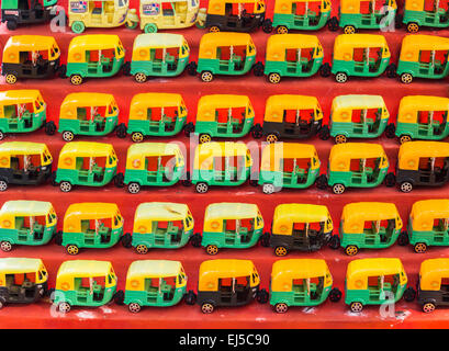 Vivacemente colorato giocattolo di plastica di tuk-tuks esposti in vendita come souvenir turistici a Fort Cochin, Kerala, India meridionale: rosso, giallo verde Foto Stock