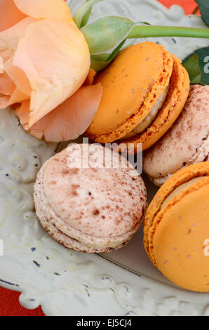 Caramello e vaniglia amaretti in ciotola vintage su Orange e legno scuro impostazione tabella. Foto Stock