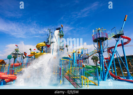 Acqua correre verso il basso dal gigantesco cilindro oscillante sulla parte superiore di Acqua Costruzione di scorrimento. Vinpearl Land Water Park, l'isola di Phu Quoc, Vietnam. Foto Stock