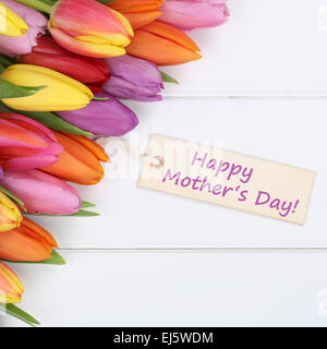 Felice giorno della madre con tulipani colorati fiori su un bianco tavola di legno con biglietto di auguri Foto Stock