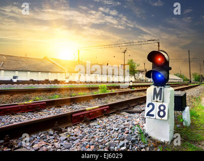 Il semaforo ferroviario vicino stazione industriale al tramonto Foto Stock