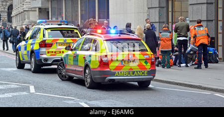 Osservatore ufficiale Medics & polizia con gli osservatori assistono pedone sul marciapiede ricevendo assistenza medica parcheggiato veicoli di emergenza City 0f Londra Regno Unito Foto Stock