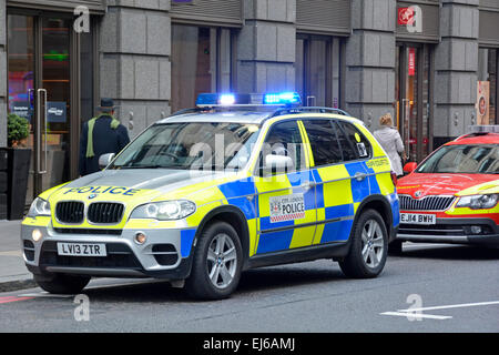 Luci blu sulla City of London BMW team di polizia che partecipa a un incidente di emergenza stradale a supporto dei paramedici in auto rossa City of London Inghilterra Regno Unito Foto Stock