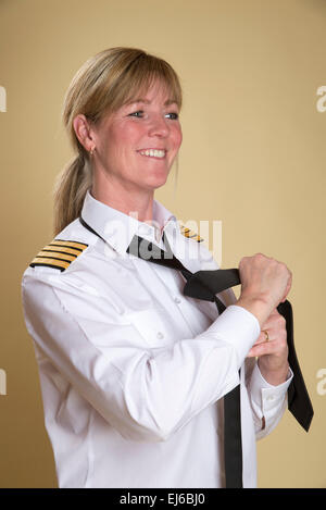 Femmina capitano della compagnia aerea di legatura uniforme il suo nodo di cravatta Foto Stock