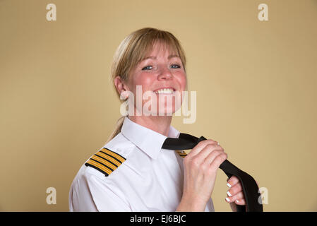 Femmina capitano della compagnia aerea di legatura uniforme il suo nodo di cravatta Foto Stock