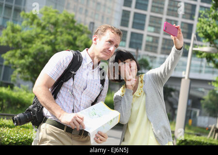 Giovane ragazza giapponese tenendo selfie con i turisti stranieri Foto Stock