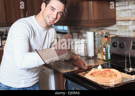 Giovane uomo in cucina godendo la pizza Foto Stock