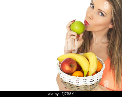 Fiducioso felice giovane donna in possesso di un paniere di freschi maturi Sano frutta mista isolata contro uno sfondo bianco con un tracciato di ritaglio e spazio di copia Foto Stock