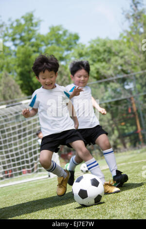 Due ragazzi stanno giocando a calcio sul parco giochi Foto Stock