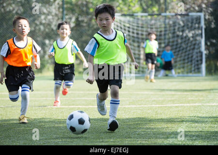 I ragazzi che giocano a calcio nel parco giochi Foto Stock